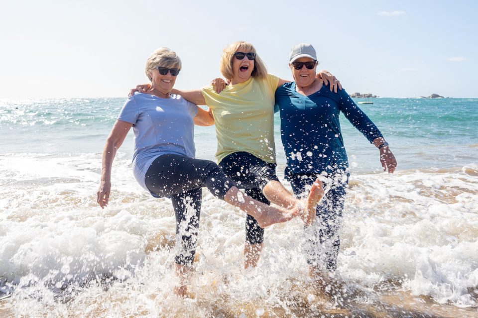 Group of three senior women walking having having fun on beach