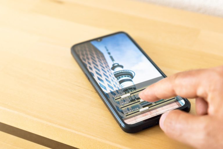 Hand editing a photo on a mobile phone. Adjusting contrast