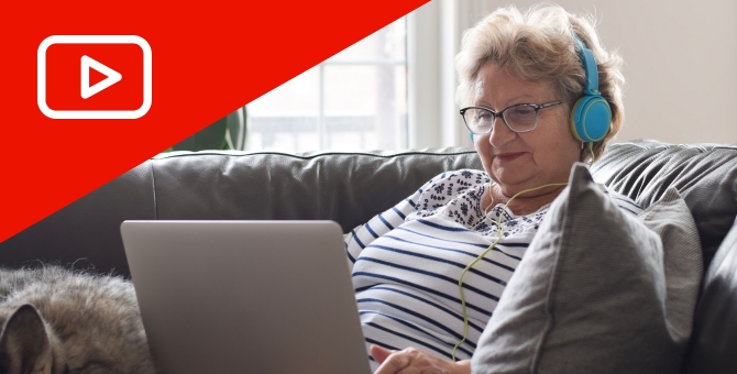 senior woman wearing headphones watching video on laptop computer