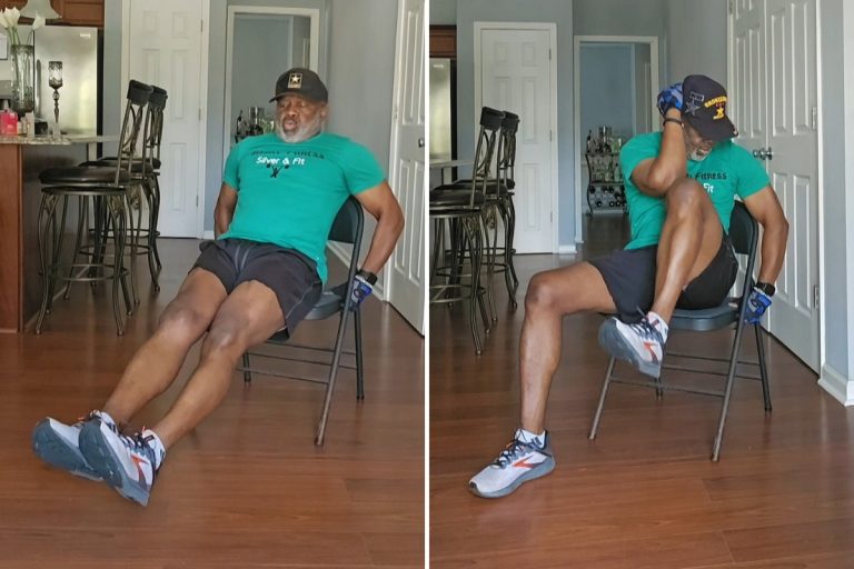 Senior African American man in green shirt and black shorts doing core exercises while seated in chair