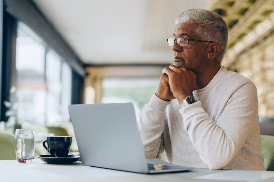 Mature businessman looking away thoughtfully while working in a modern cafe