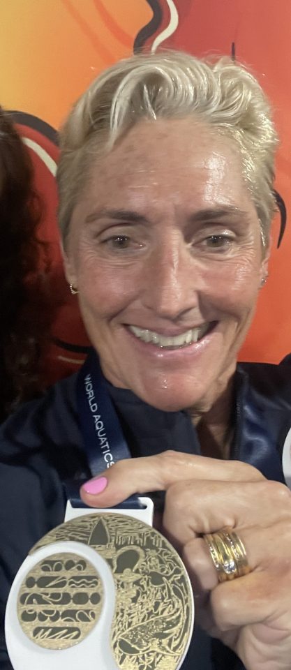 senior woman holding swimming medal