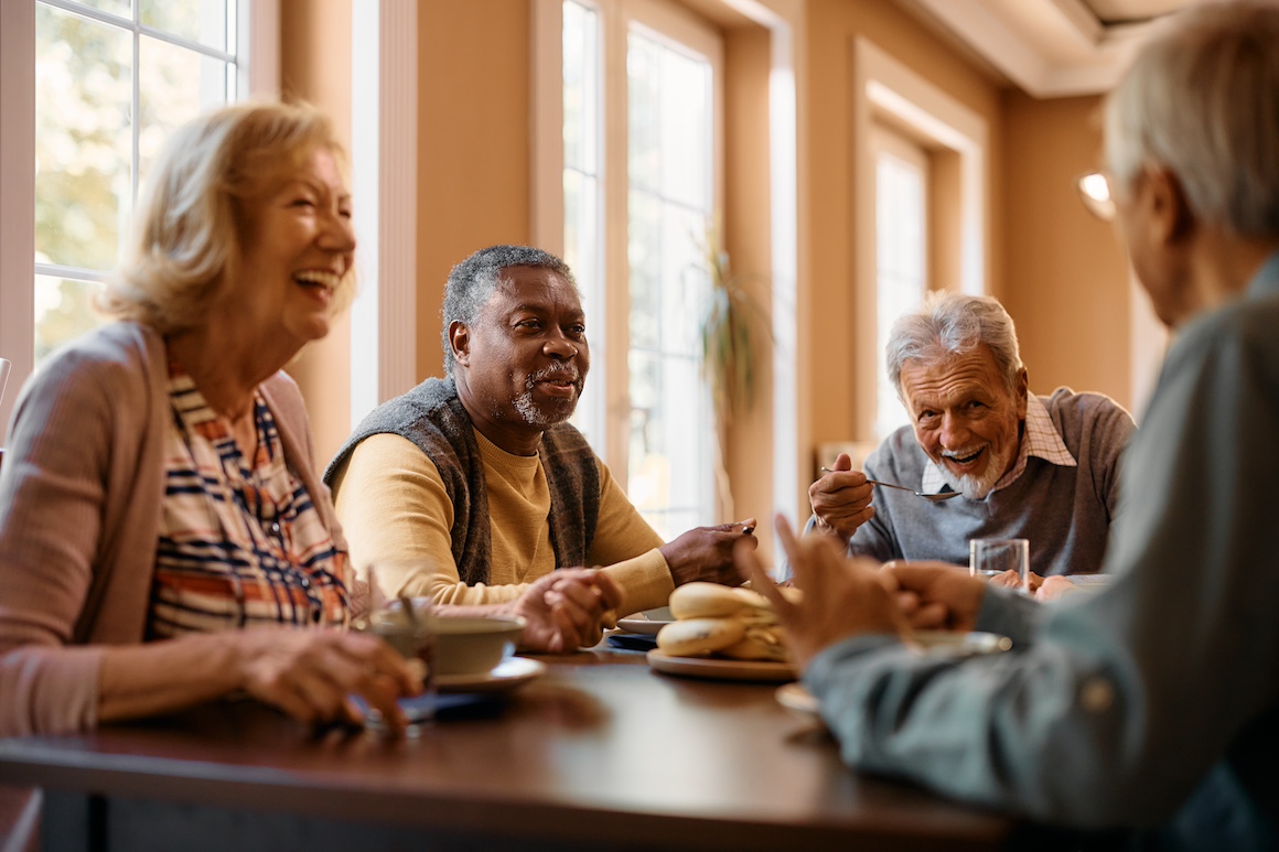 Group of cheerful senior people enjoy in conversation during lunch