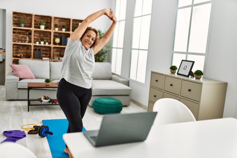 Middle age caucasian woman having stretching online class at home