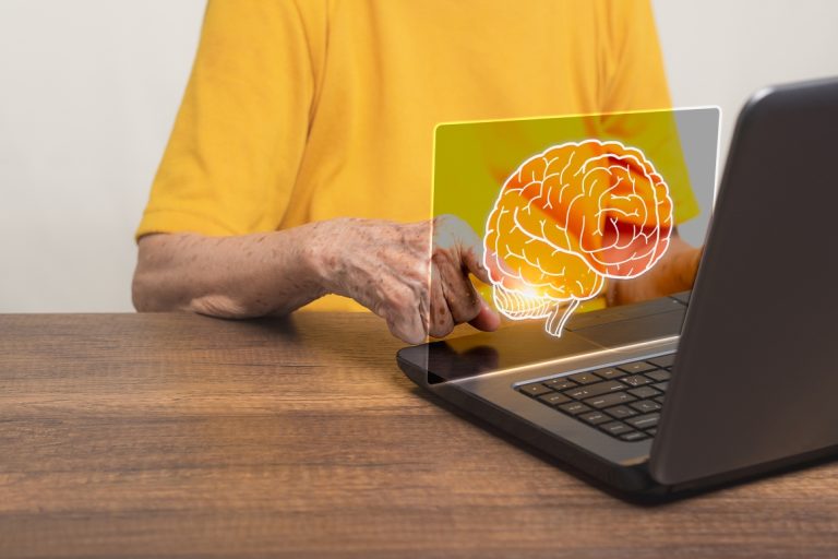 Person sitting in from of laptop looking at a projected Image of a brain.
