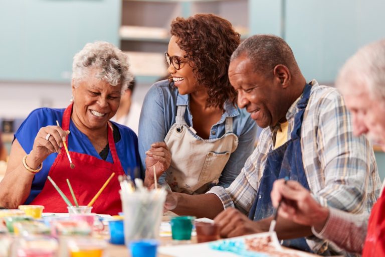 Group Of Seniors Attending Art Class In Community Center With Teacher