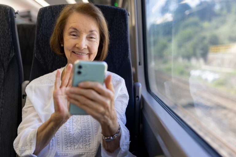 Woman traveling solo on a train using apps on her mobile phone.