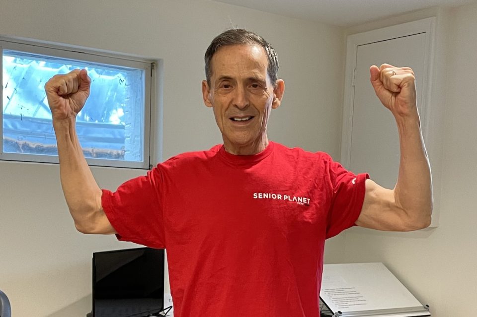 man in red Senior Planet shirt flexing arms