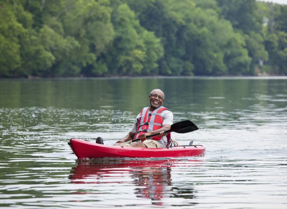 Smiling senior Black man kayaking on river