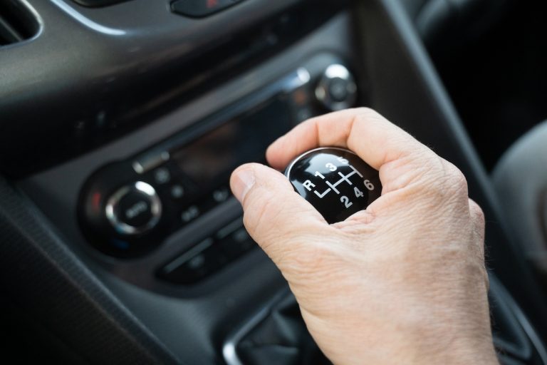 A person changes gear while driving in a car.
