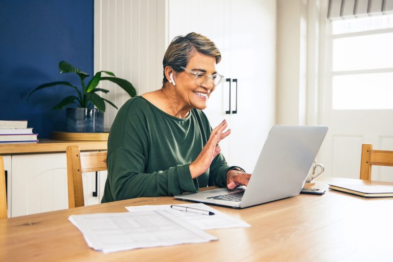 senior latina woman sitting at home and using her laptop for a video call