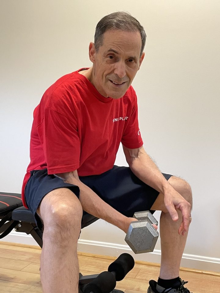 senior man in red shirt lifting dumbbell