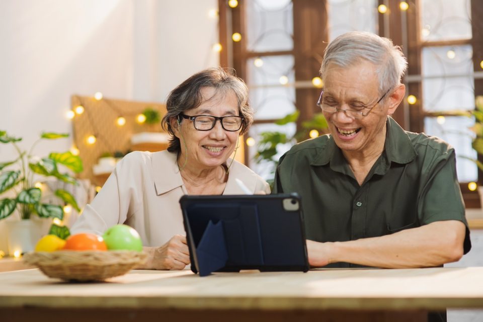senior couple taking class on digital tablet in living room at home