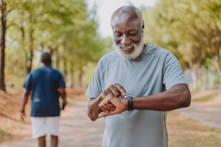 Portrait of a senior man looking at his smart watch during physical exercise in public park