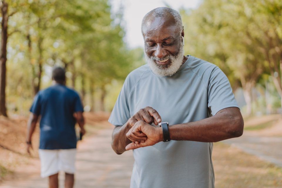 Portrait of a senior man looking at his smart watch during physical exercise in public park
