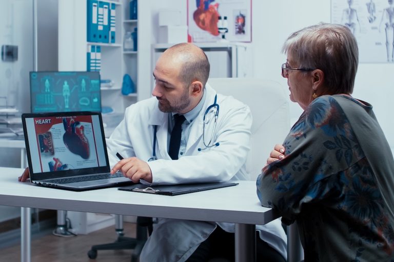 male doctor showing heart information to senior female patient on computer screen