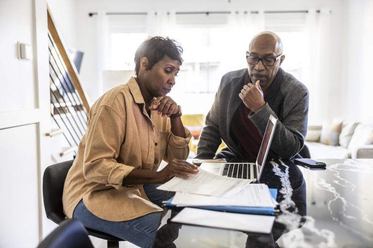 Senior couple using laptop and paying bills at home