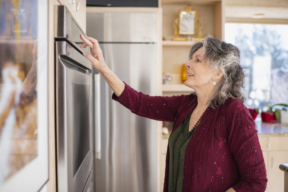 senior woman setting oven in her home kitchen